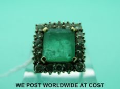 An 18ct gold ring set with a large square cut emerald surrounded by round cut diamonds in a square