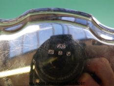 A hallmarked silver salver with shaped edge, raised on three feet, London 1970 maker HB,