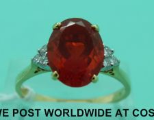 An 18ct gold ring set with a large oval cut fire opal and three diamonds to each shoulder (size U)