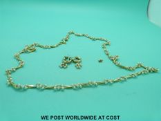 A pair of yellow metal earrings with drop pearls and a necklace