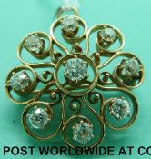 A yellow metal pendant/ brooch set with nine old cut diamonds in a stylised floral design,