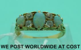 A Victorian/Edwardian yellow metal ring set with three opal cabochons and four old cut diamonds