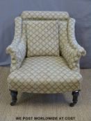 An upholstered 19th century armchair with ebonised turned front legs