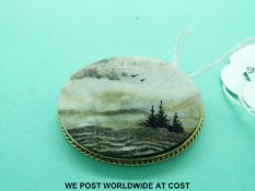 A 9ct gold brooch set with an oval section of agate with added detail to depict a landscape,
