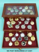 Forty highly decorated pocket watches in a fitted three drawer pocket watch collectors' cabinet.