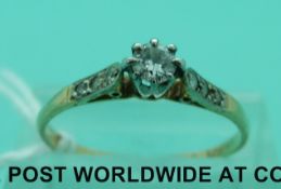 An 18ct gold ring with a central diamond and diamonds to the shoulders (size Q)