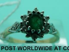A 9ct gold ring set with an emerald surrounded by diamonds (size M)