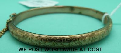 A 9ct gold bangle with engraved foliate decoration (8.