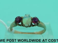 A yellow metal ring set with opal cabochon and two rubies (size L)