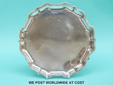 A hallmarked silver salver with shaped edge raised on three hoof feet, Sheffield 1963 maker C.J.