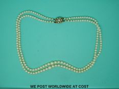 A double strand of pearls with a 9ct gold clasp set with a zircon and pearls