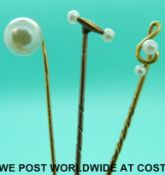 A yellow metal stick pin in the form of a treble clef set with seed pearls,