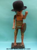 A Japanese papier mache wood and raffia articulated figure holding a gong and wearing a bowler hat,