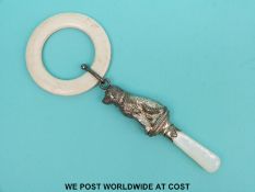 A hallmarked silver rattle in the form of a seated dog with mother of pearl handle and attached