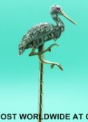 A yellow metal stick pin in the form of a stork set with rose cut diamonds and a ruby eye in