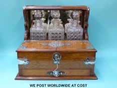 An early 20thC oak tantalus with silver plated mounts, double flaps to front revealing compartments,