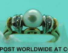 An 18ct gold ring set with a pearl flanked by diamonds (size H)