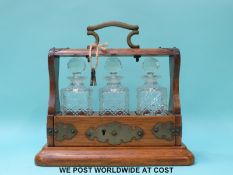 An oak bachelor's or miniature tantalus with three cut glass bottles, length 25.