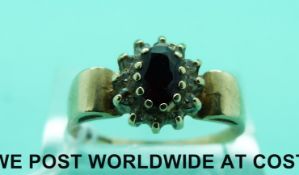 A 9ct gold ring set with a garnet and clear stones (size R)