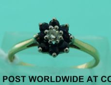 An 18ct gold ring set with a diamond surrounded by sapphires (size M)