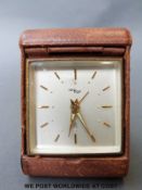 A Swiss 8 day leather cased travel alarm clock with square dial,