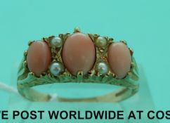 A 9ct gold ring set with three coral cabochons and seed pearls (size R)