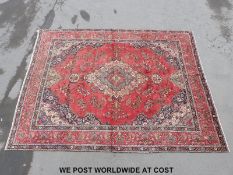 A large Persian rug with central motif on a red ground (386 x 293cm)