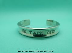 A silver bangle marked Tiffany & Co,