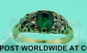 An 18ct gold ring set with a cushion cut apple green emerald and three diamonds to each side (size