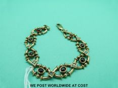 A yellow metal bracelet marked 9ct gold set with alternating garnet and opal cabochons (14.