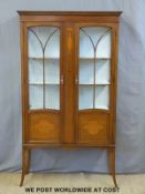 An Edwardian inlaid mahogany glazed cabinet raised on slender tapering legs (W97 x D33 x H172cm)