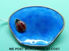 A silver brooch set with blue guilloche enamel and an enamel ladybird,