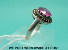 A silver ring set with an oval cut pink sapphire (size P)