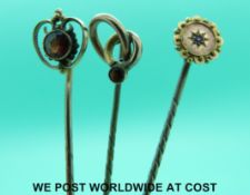 Two 9ct gold stick pins each set with a garnet and an Edwardian stick pin set with a ruby to the