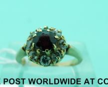 A yellow metal ring set with a garnet surrounded by diamonds (size J)