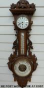 A circa 1900 ornately carved oak aneroid barometer/clock compendium,