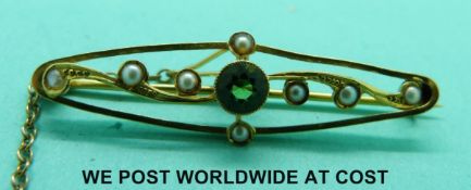 An Edwardian yellow metal brooch marked 15ct set with a peridot and seed pearls
