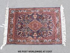 A small Perisan rug with central motif against a blue ground (1m x 63cm)