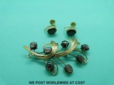 A yellow metal brooch marked 18ct set with black cat's eye sapphire cabochons with a pair of