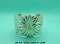 A silver cuff bangle marked Tiffany & Co with daisy design, the daisies having gilt centres,