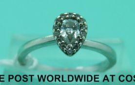 A 9ct white gold ring set with a pear cut diamond surrounded by further smaller diamonds,