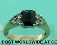 A 14ct gold ring set with an emerald cut sapphire with three diamonds to each shoulder (size N)