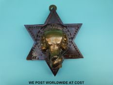 A 19th/20th century Anglo Indian brass elephant bust mounted on a carved star shaped plaque,