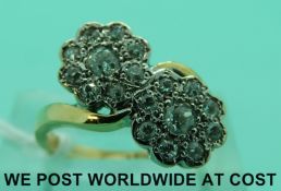 An 18ct gold ring set with old cut diamonds in two flower clusters in a twist setting (Size K)