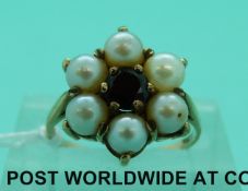 A yellow metal ring marked 9ct gold set with a garnet to the centre surrounded by pearls (size K)