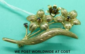 A 9ct gold brooch in the form of three flowers set with garnets (5.