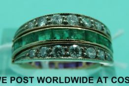 A yellow metal ring set with square cut rubies to one side and square emeralds to the other with