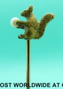 A yellow metal stick pin in the form of a squirrel holding a pearl as a nut