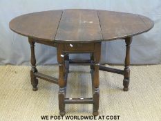 An antique oak drop leaf table with peg joints raised on turned legs united by moulded stretchers