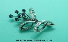 A white metal brooch marked 750 set with diamonds and sapphires,